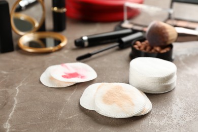 Photo of Dirty cotton pads and cosmetic products on grey table