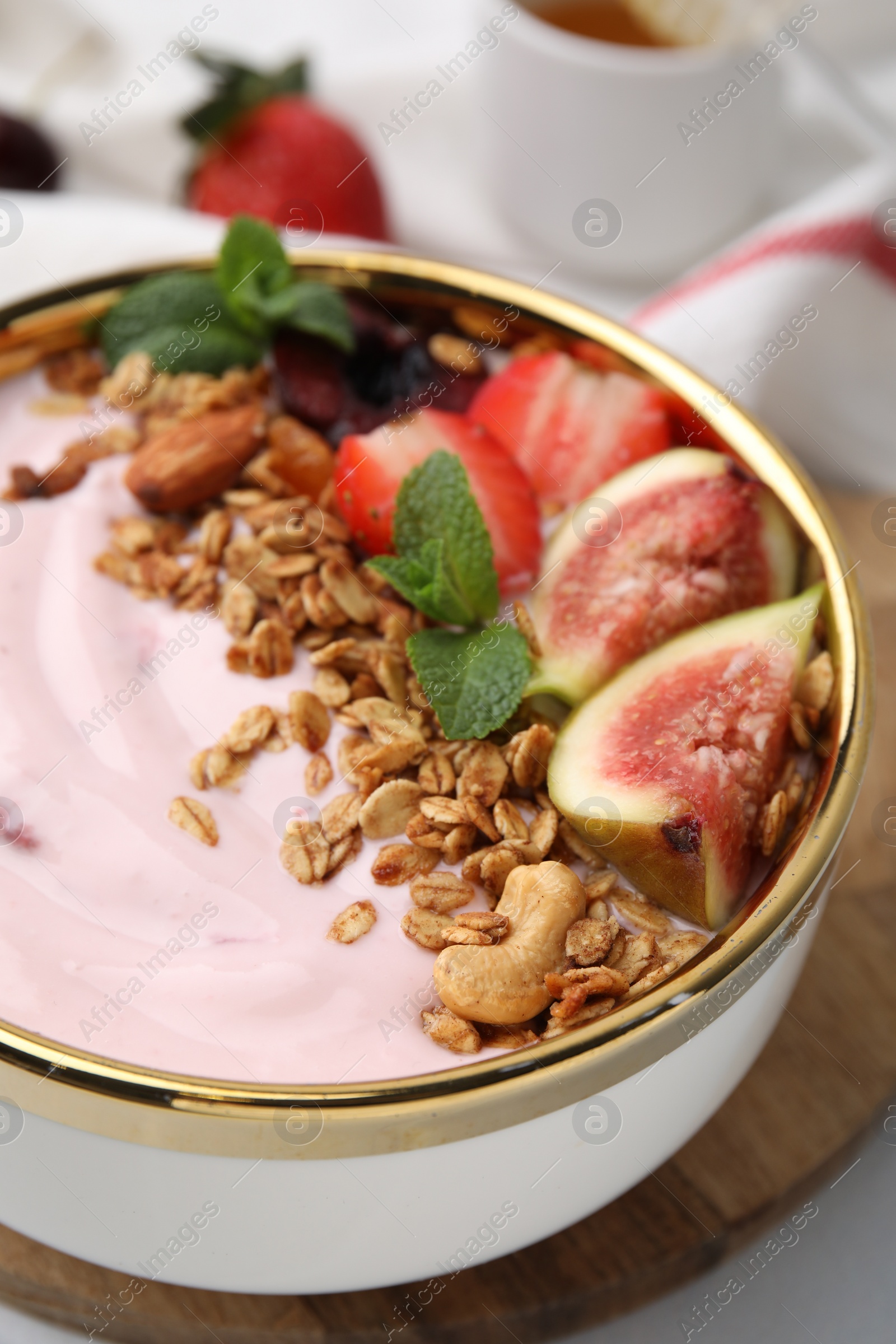 Photo of Bowl with yogurt, fruits and granola on white table, closeup