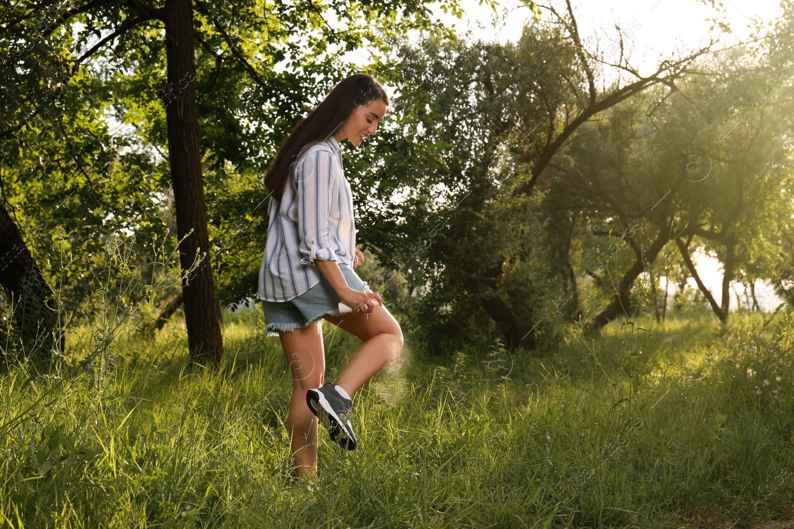 Photo of Woman applying insect repellent on leg in park. Tick bites prevention