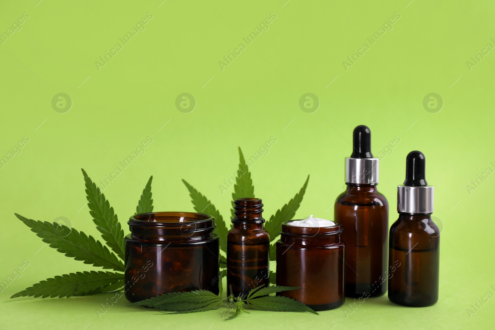 Photo of Composition with CBD oil, THC tincture and hemp leaves on light green background