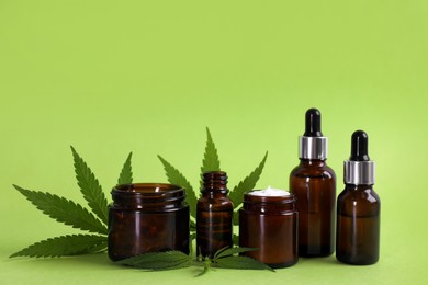 Photo of Composition with CBD oil, THC tincture and hemp leaves on light green background