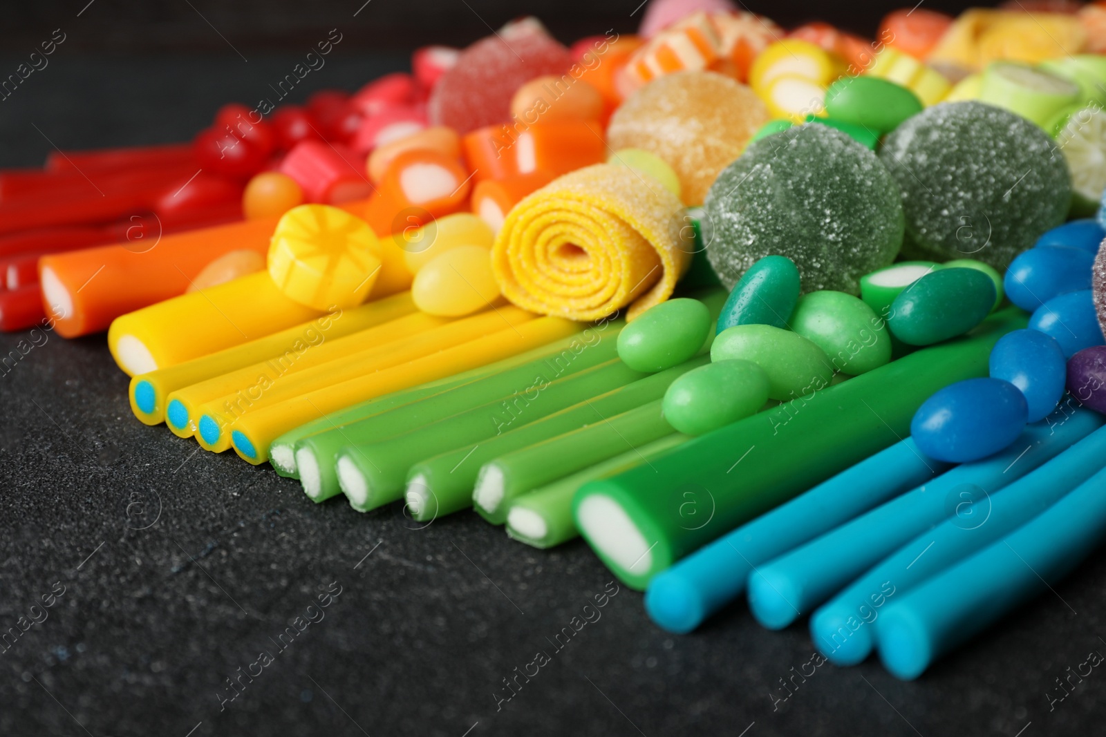 Photo of Different delicious colorful candies on dark table