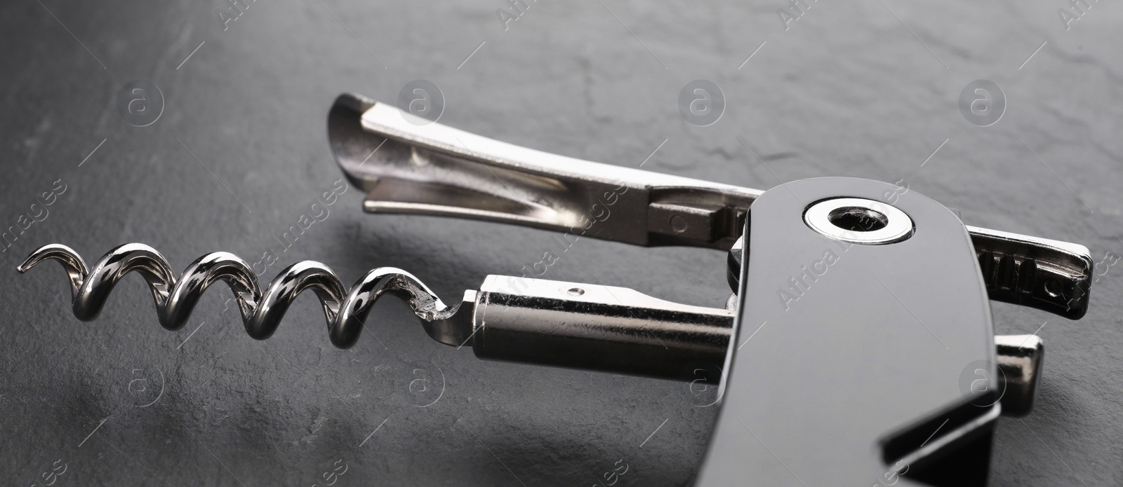 Photo of One corkscrew (sommelier knife) on grey textured table, closeup