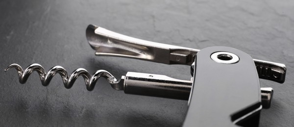 One corkscrew (sommelier knife) on grey textured table, closeup