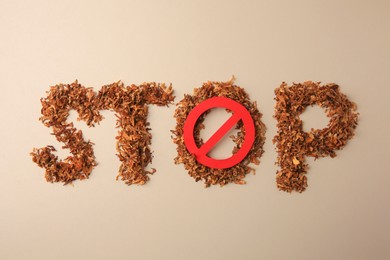 Photo of Word Stop made of dry tobacco and prohibition sign on beige background, flat lay. Quitting smoking concept