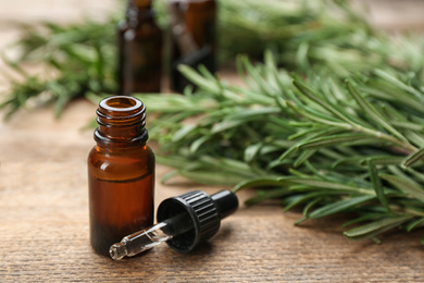 Photo of Bottle of rosemary essential oil on wooden table. Space for text