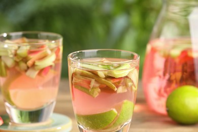 Tasty rhubarb cocktail with lime on table outdoors, closeup