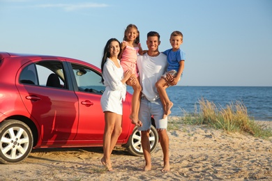 Photo of Happy family near car on sandy beach. Summer trip