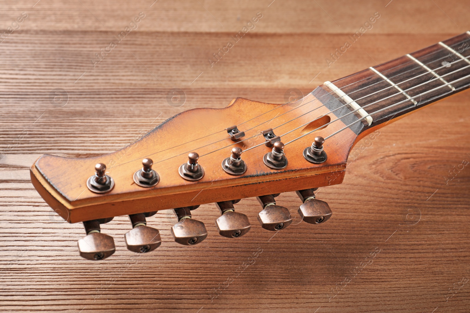 Photo of Modern electric guitar on wooden background, closeup view. Musical instrument