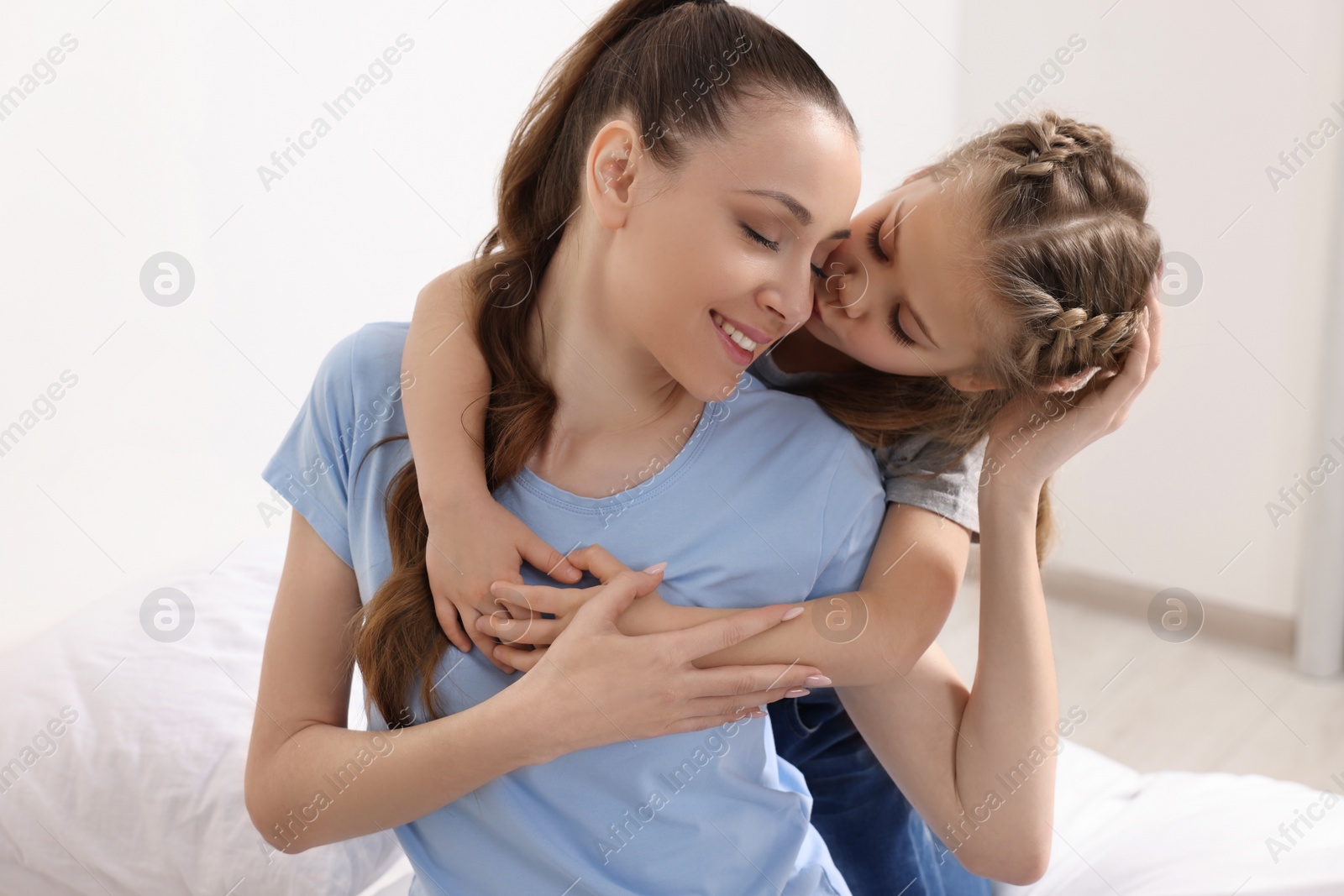 Photo of Cute daughter kissing and hugging her mom indoors