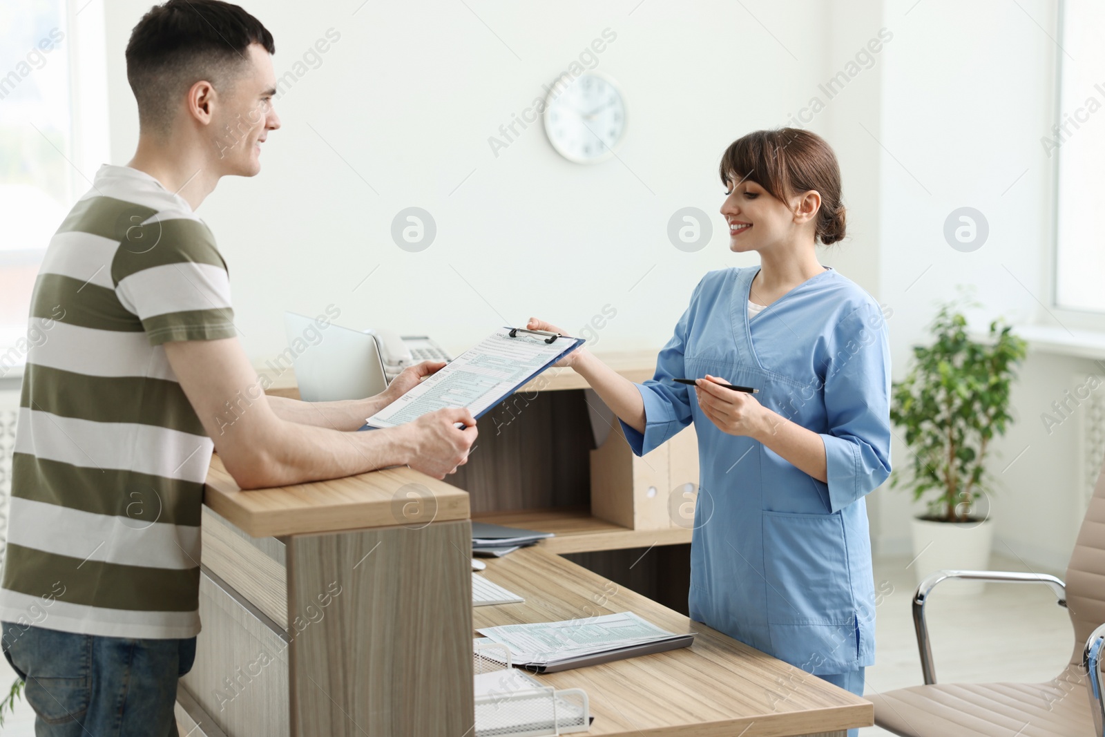 Photo of Smiling medical assistant working with patient at hospital reception