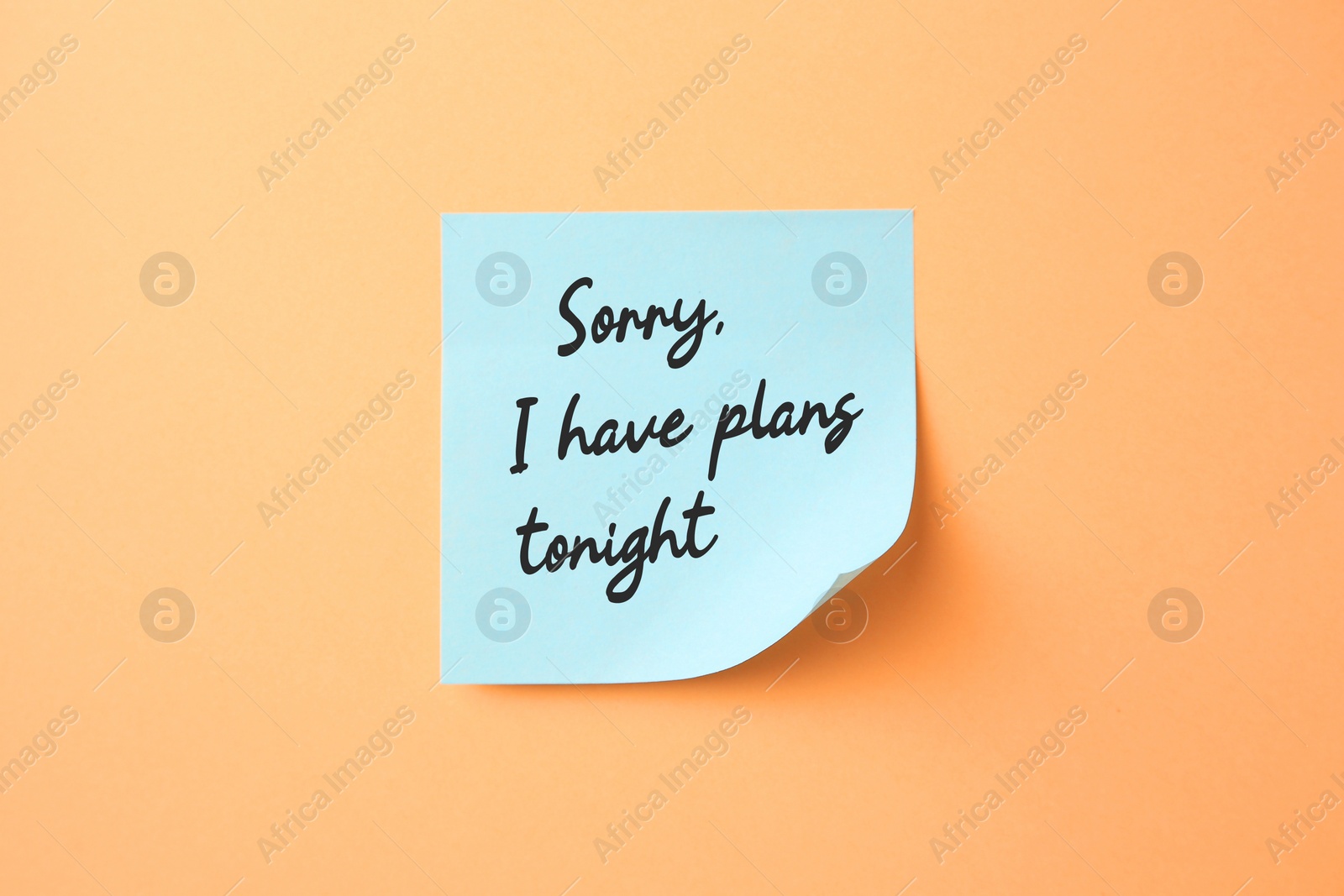 Image of Light blue sticky note with phrase Sorry, I Have Plans Tonight on pale orange background