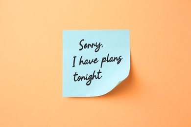 Image of Light blue sticky note with phrase Sorry, I Have Plans Tonight on pale orange background