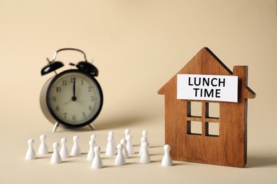Image of Business lunch time. Composition with chess pieces as employees, wooden house figure and alarm clock on beige background