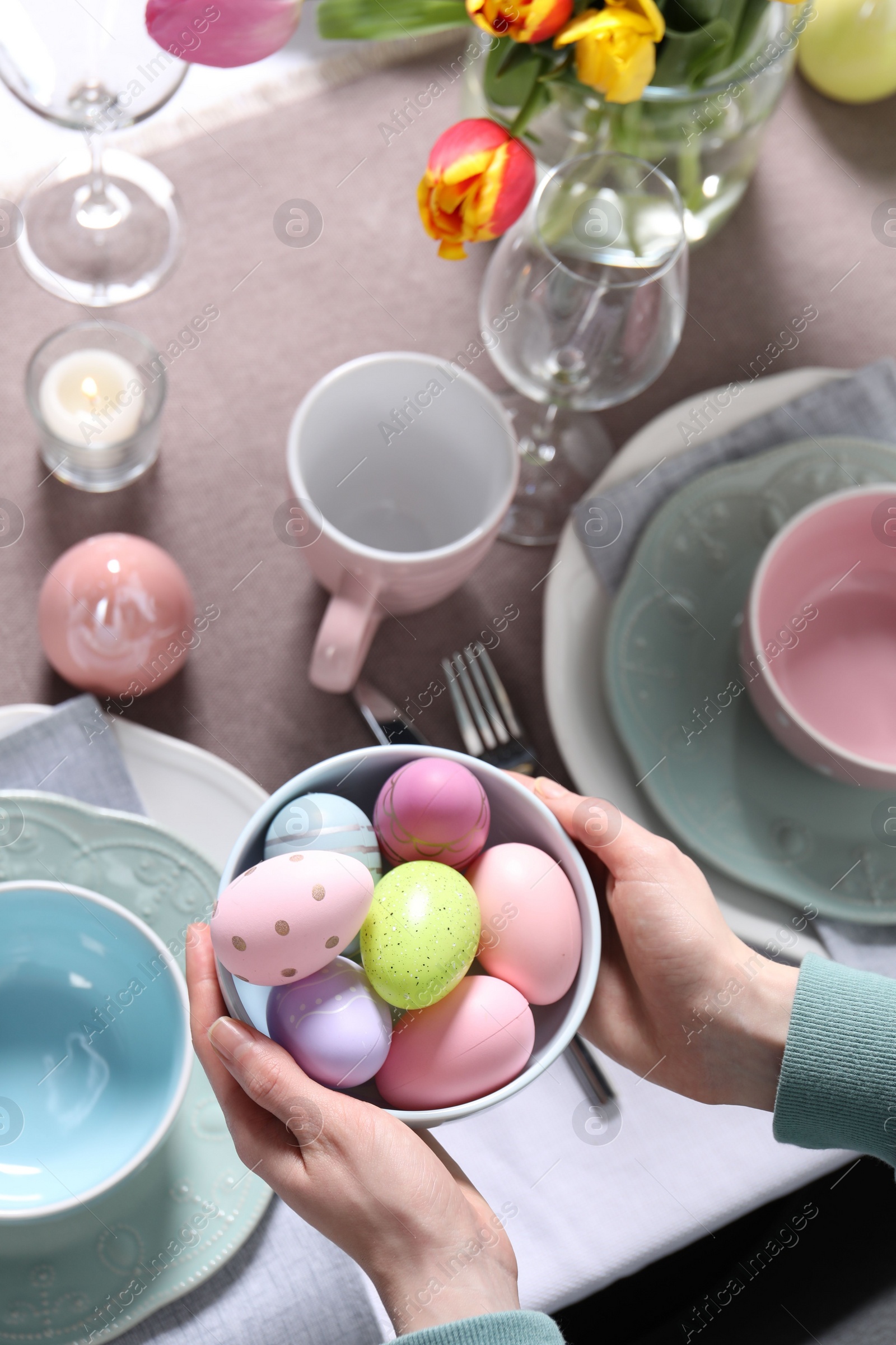 Photo of Woman setting table for festive Easter dinner at home, top view