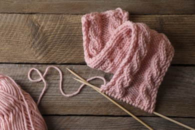 Photo of Soft pink woolen yarn, knitting and needles on wooden table, flat lay