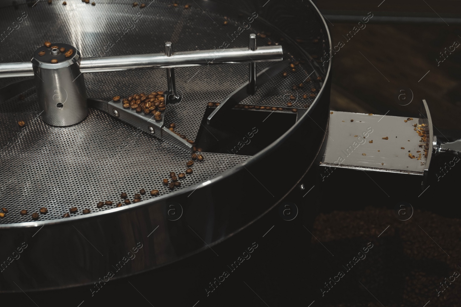 Photo of Modern coffee roaster machine with beans indoors, closeup