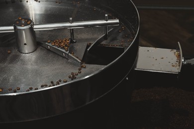 Photo of Modern coffee roaster machine with beans indoors, closeup