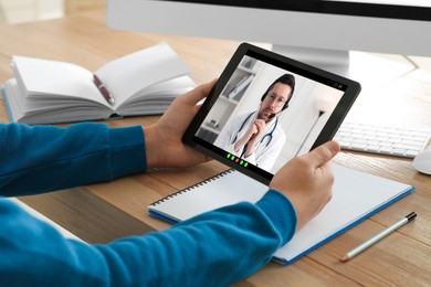 Online medical consultation. Woman having video chat with doctor via tablet at table indoors, closeup