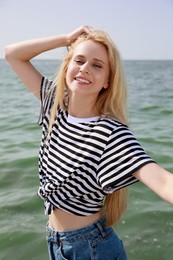 Beautiful young woman near sea on sunny day in summer