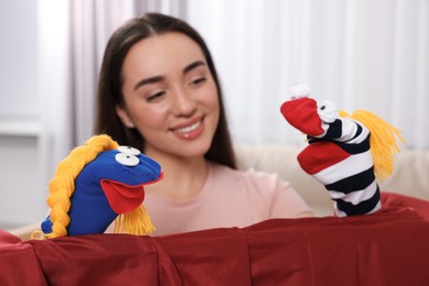 Happy woman performing puppet show at home, selective focus