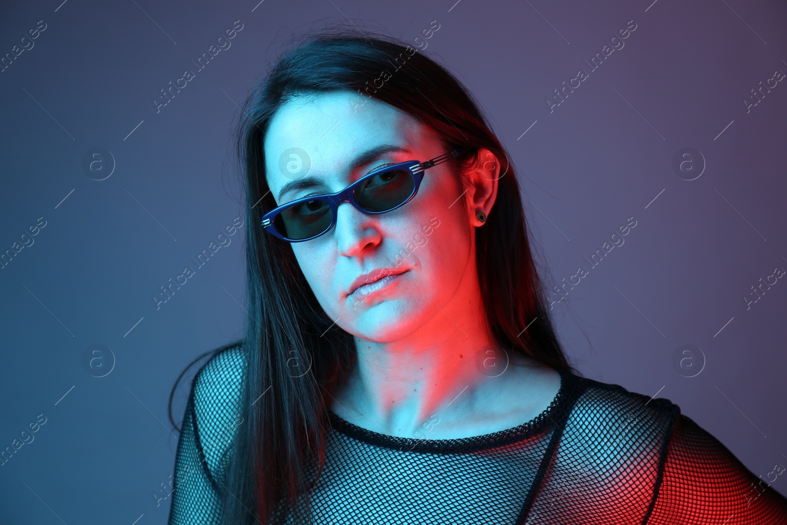 Photo of Portrait of beautiful young woman with sunglasses on color background