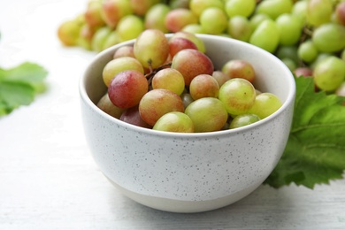 Photo of Fresh ripe juicy grapes in bowl on table, closeup