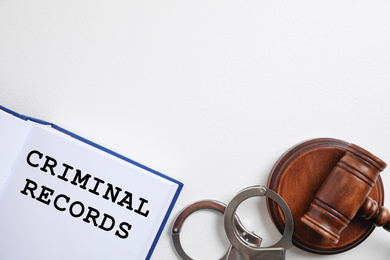 Image of Book with words CRIMINAL RECORDS, handcuffs and gavel on white background, flat lay