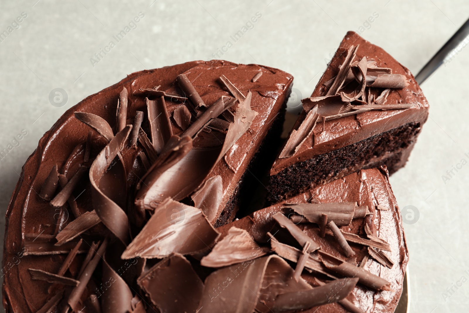 Photo of Tasty homemade chocolate cake and shovel on grey table, closeup