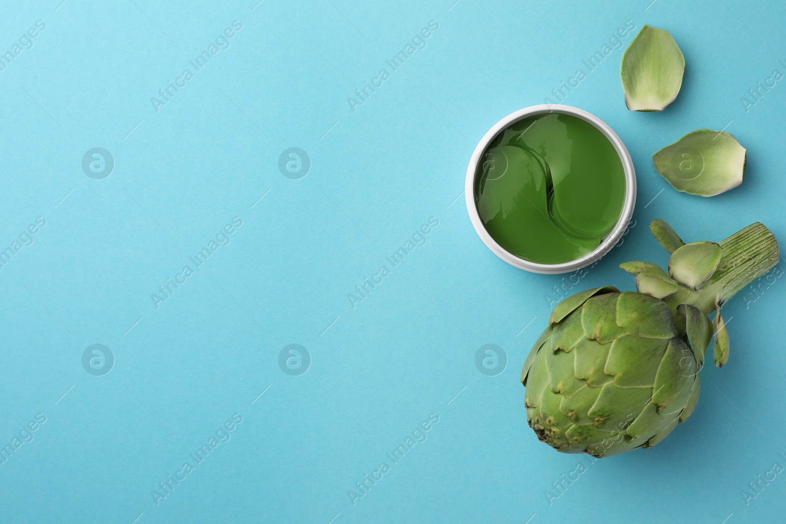 Photo of Package of under eye patches and artichoke on light blue background, flat lay with space for text. Cosmetic product