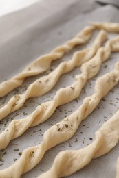 Homemade breadsticks with spices on baking sheet, closeup. Cooking traditional grissini