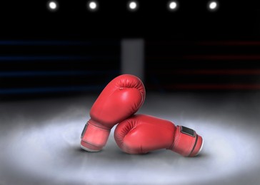 Image of Pair of boxing gloves on ring in darkness