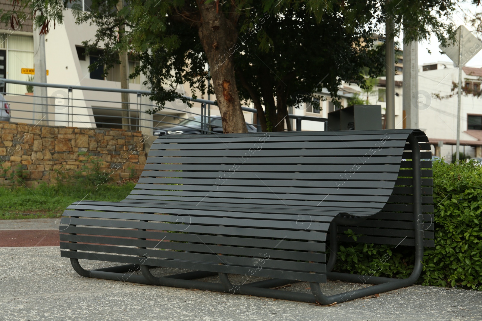 Photo of Beautiful view of black wooden bench and plants in park