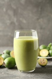 Photo of Fresh feijoa smoothie and fresh fruits on grey table, closeup