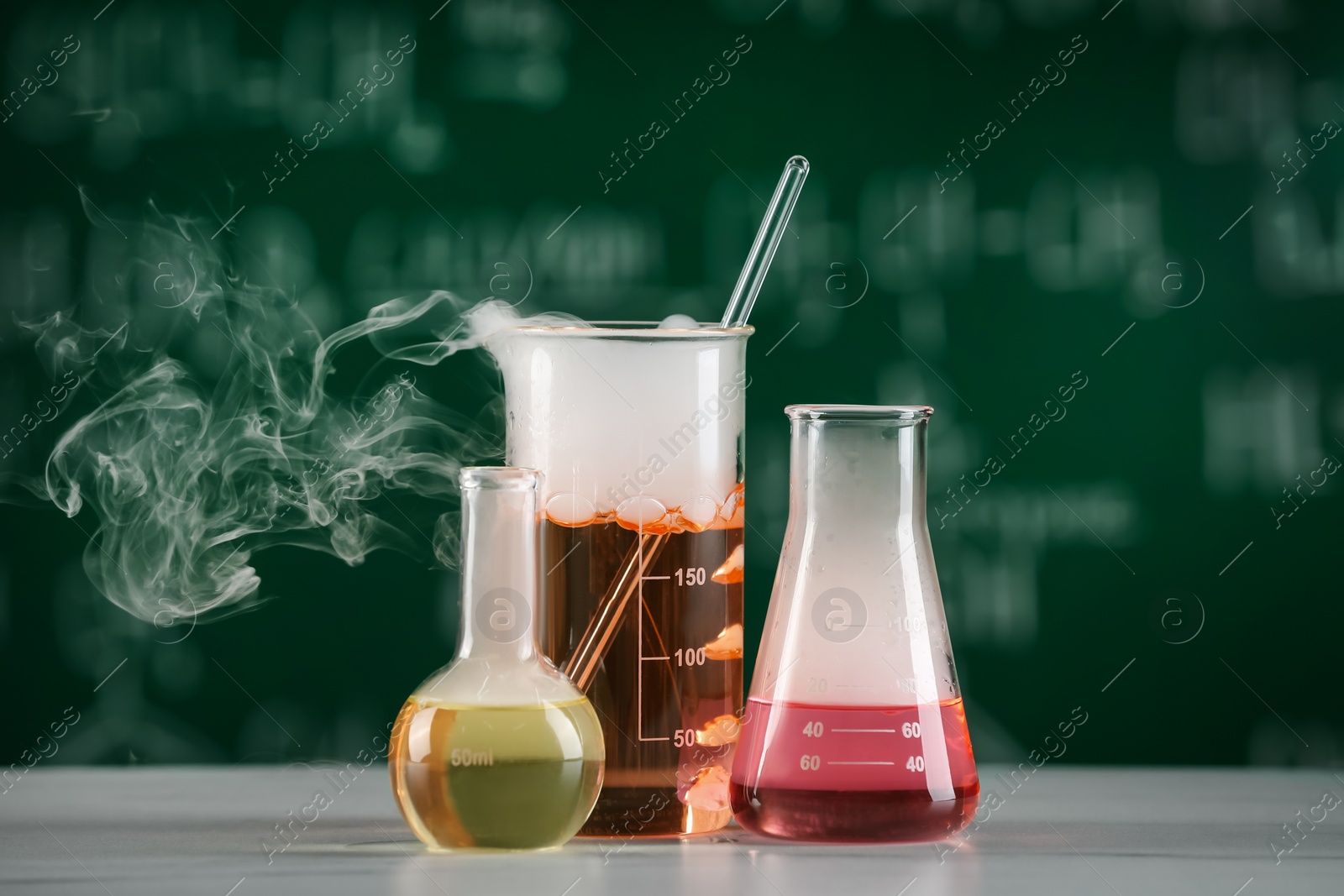 Photo of Laboratory glassware with colorful liquids on white table. Chemical reaction