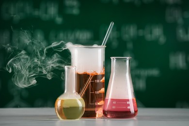 Laboratory glassware with colorful liquids on white table. Chemical reaction