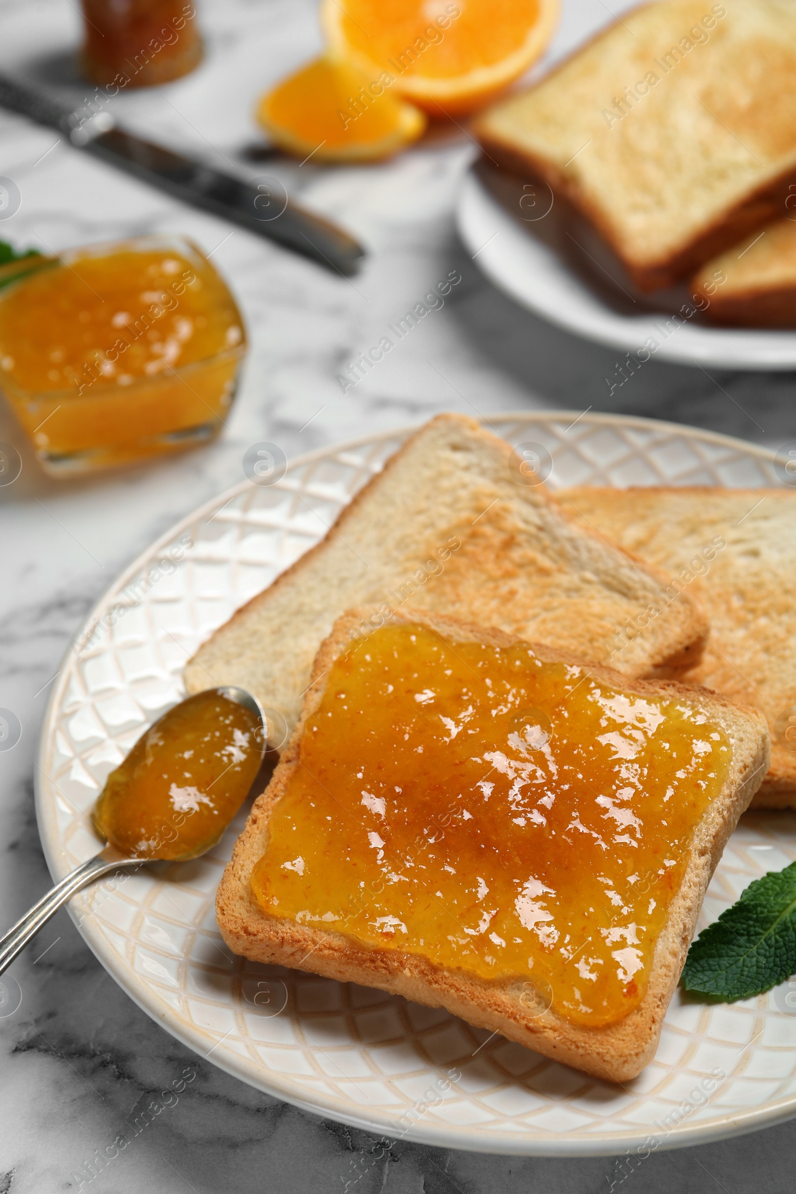 Photo of Delicious toasts with jam and mint on white marble table, closeup