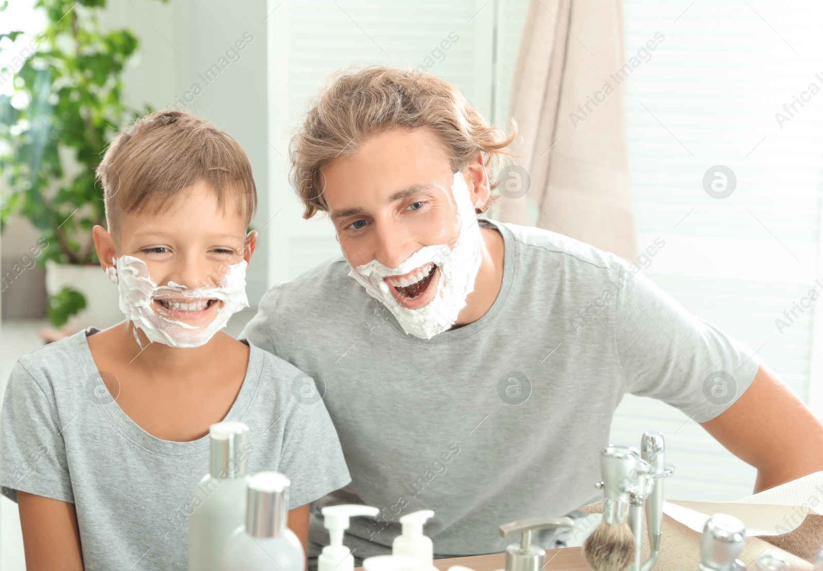 Photo of Father and son with shaving foam on faces in bathroom