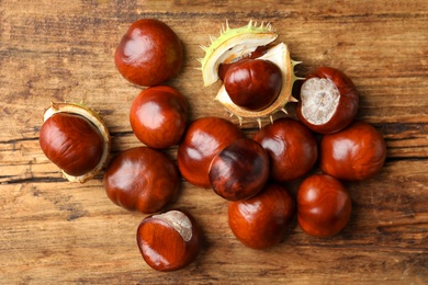 Many horse chestnuts on wooden table, flat lay