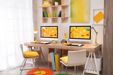 Modern workplace with large desk and computers in room. Stylish interior