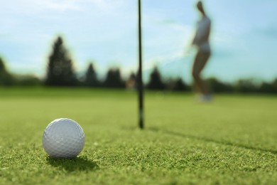Photo of Woman playing golf at green course, focus on ball. Space for text