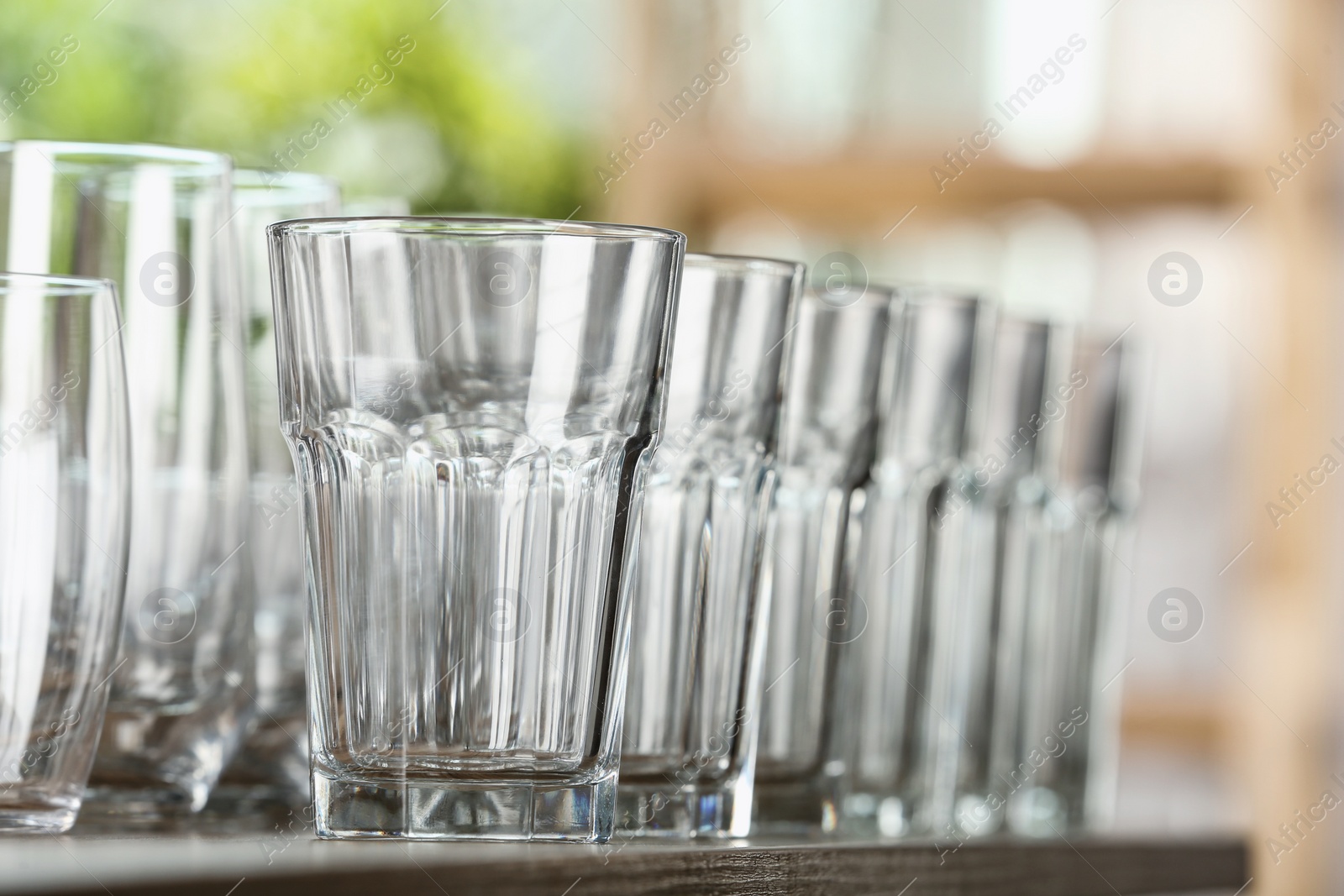 Photo of Empty glasses on wooden table against blurred background