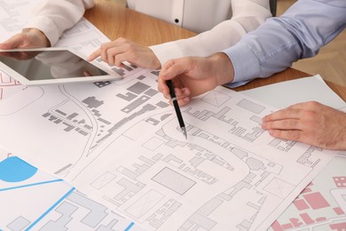 Professional cartographers working with cadastral map at table, closeup