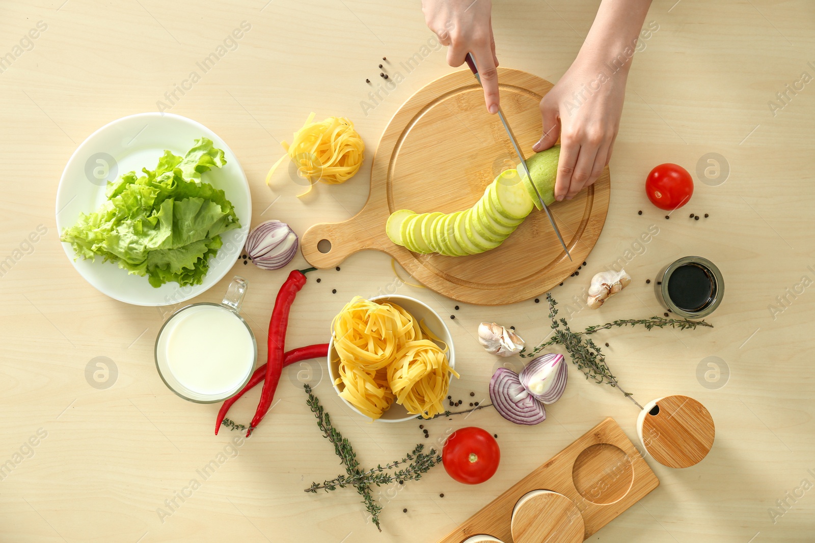 Photo of Woman cooking food at wooden kitchen table, flat lay