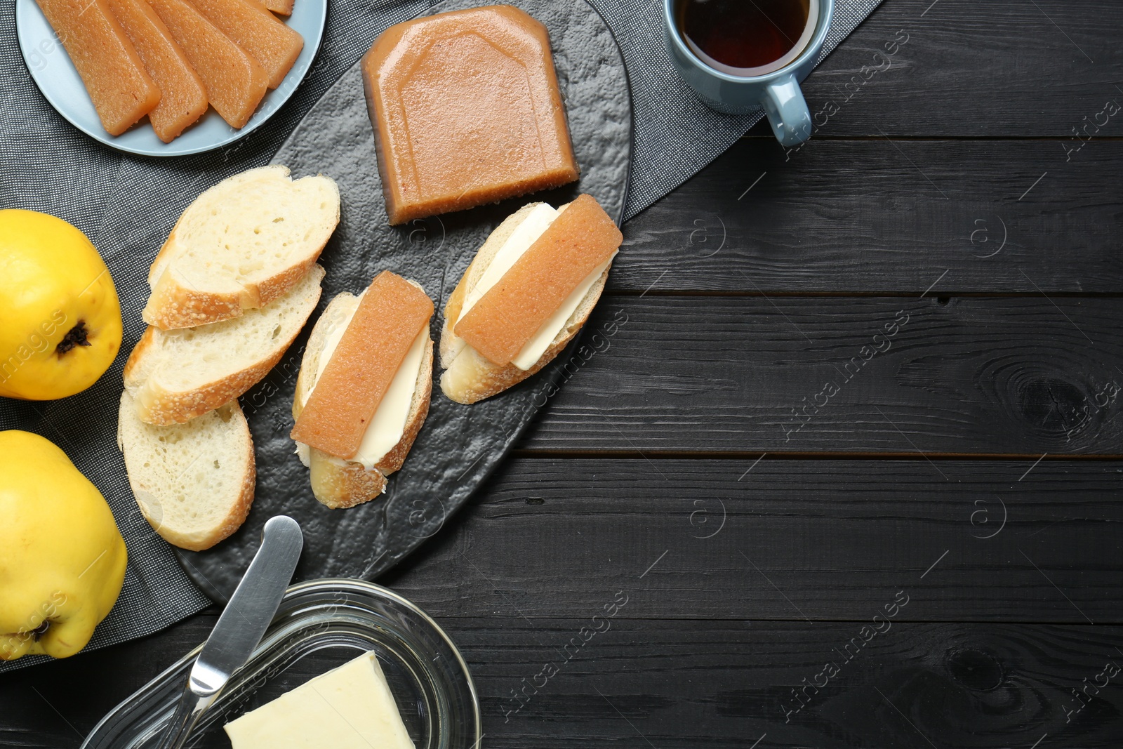 Photo of Tasty sandwiches with quince paste served on black wooden table, top view. Space for text