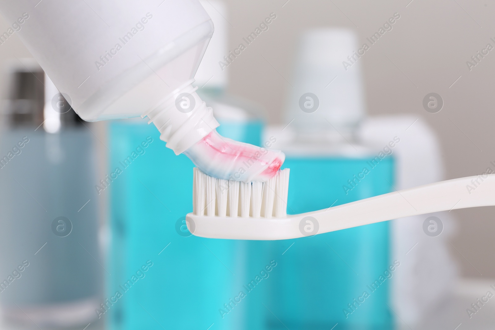 Photo of Applying paste on toothbrush near mouthwash, closeup