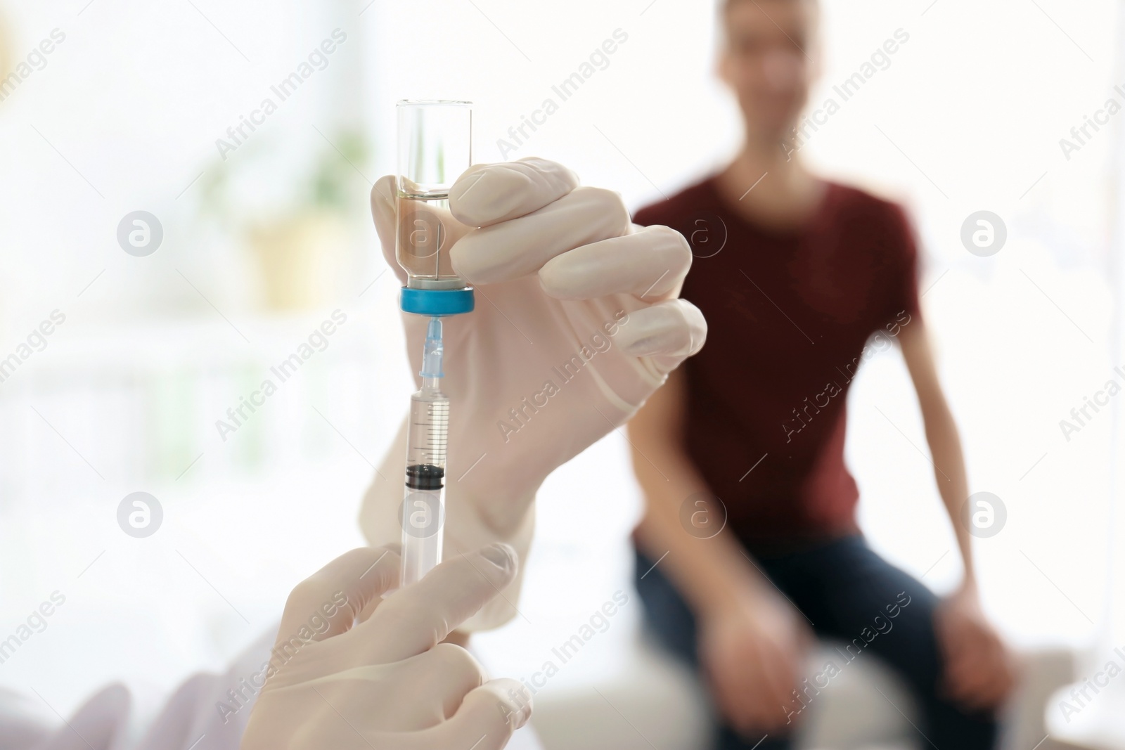 Photo of Doctor holding ampule with vaccine and syringe for patient in clinic, closeup