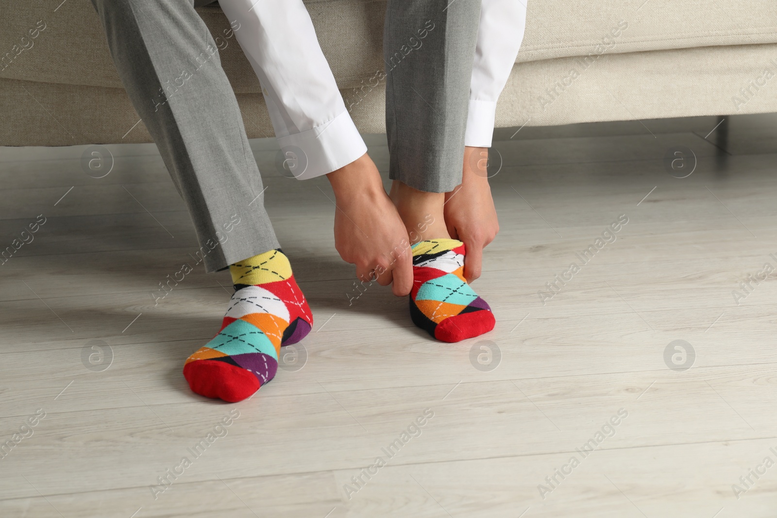 Photo of Man putting on colorful socks indoors, closeup