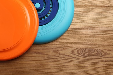 Photo of Plastic frisbee disks on wooden background, flat lay. Space for text