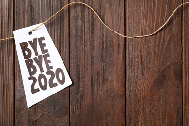 Photo of Sheet of paper with phrase Bye Bye 2020 on wooden table, top view. Space for text